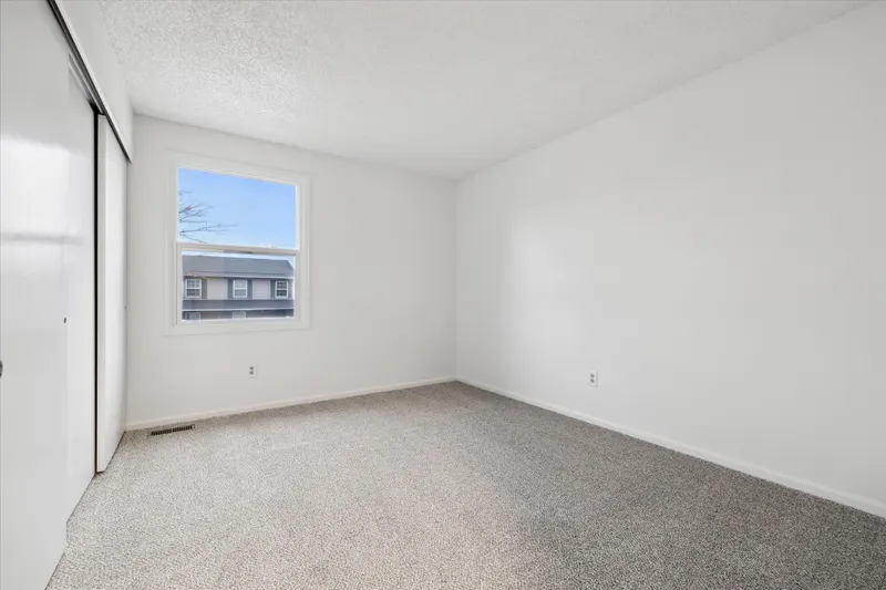 Same bedroom after neutral paint, white closet doors, and new carpet