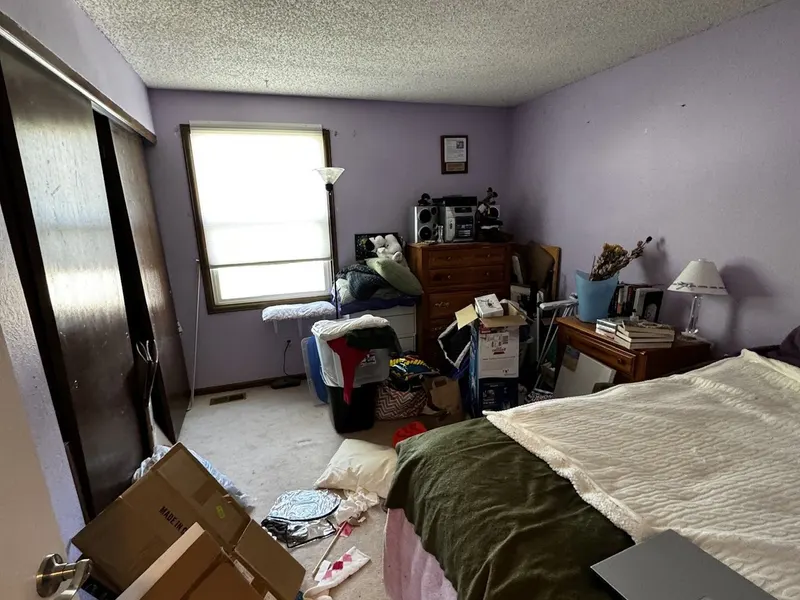 Bedroom before prep: purple walls, dark closet doors, and moving boxes