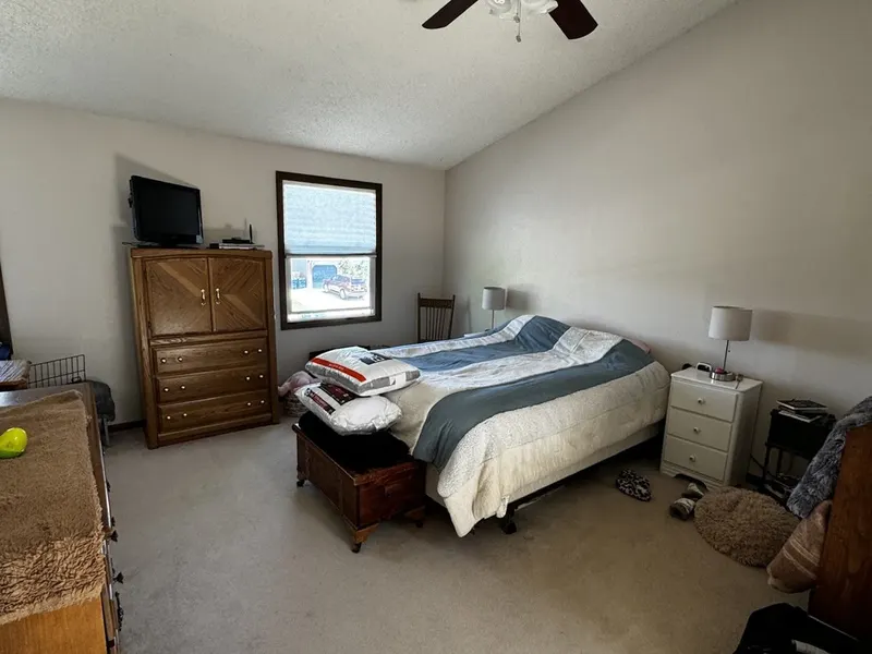 Primary bedroom before: dated furniture, packed with belongings